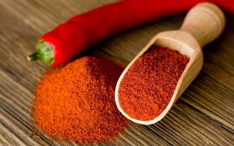 red hot paprika powder on a wooden spoon