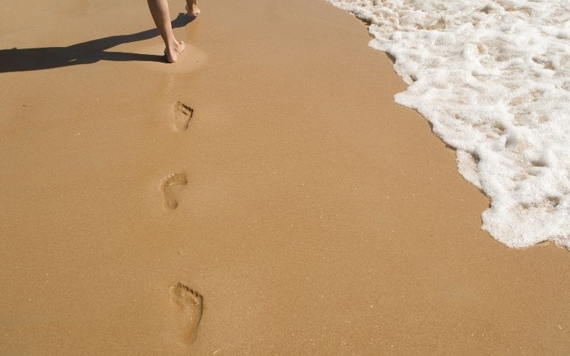 footprints in the sand with approaching tide