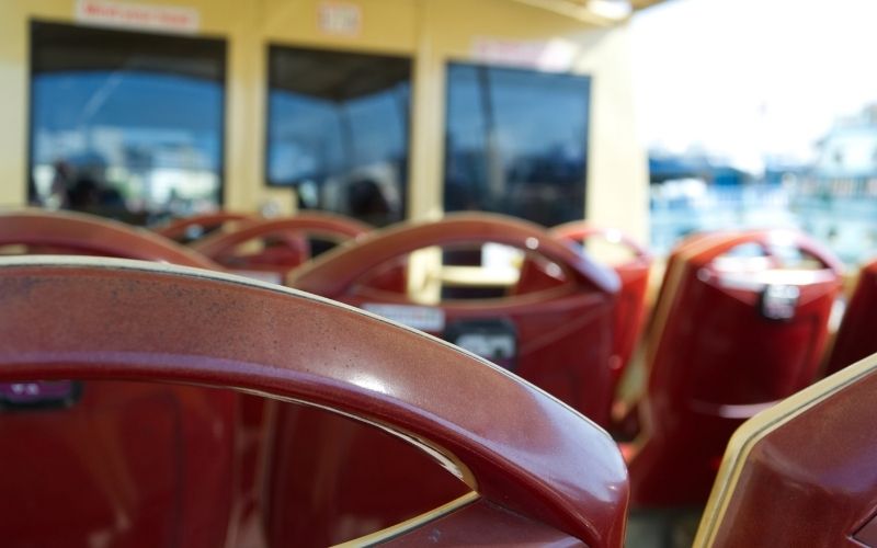 Photo of several red colored back of chair from inside of a bus