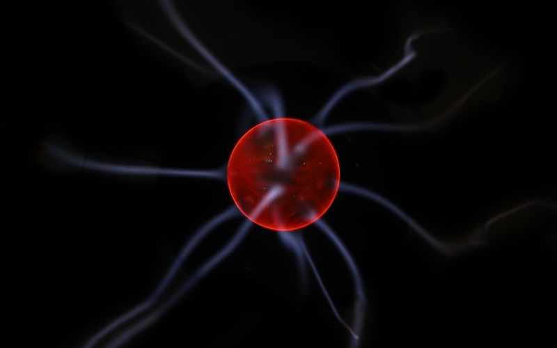 image showing red colored sphere with blue lines around ot in black background