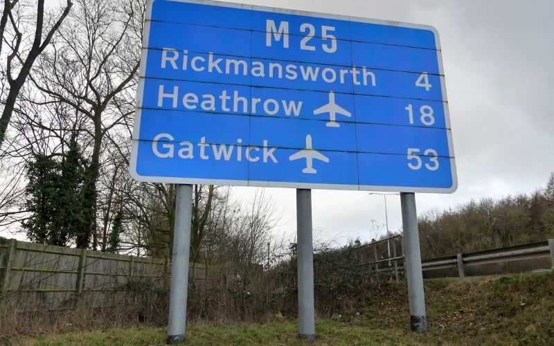 Photo of a large sign board with texts that reads M25, Rickmansworth, Heathrow, and Gatwick