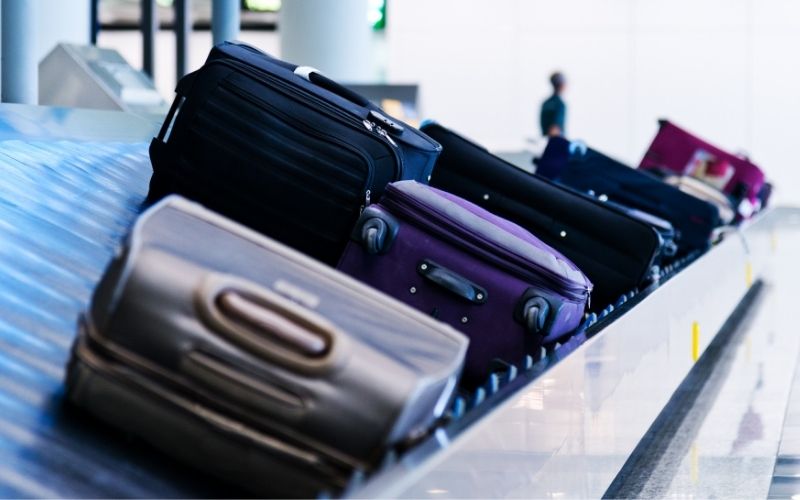 Photo of several luggage on a conveyor inside an airport