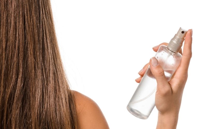 Photo of a woman in her back holding a bottle with liquid inside