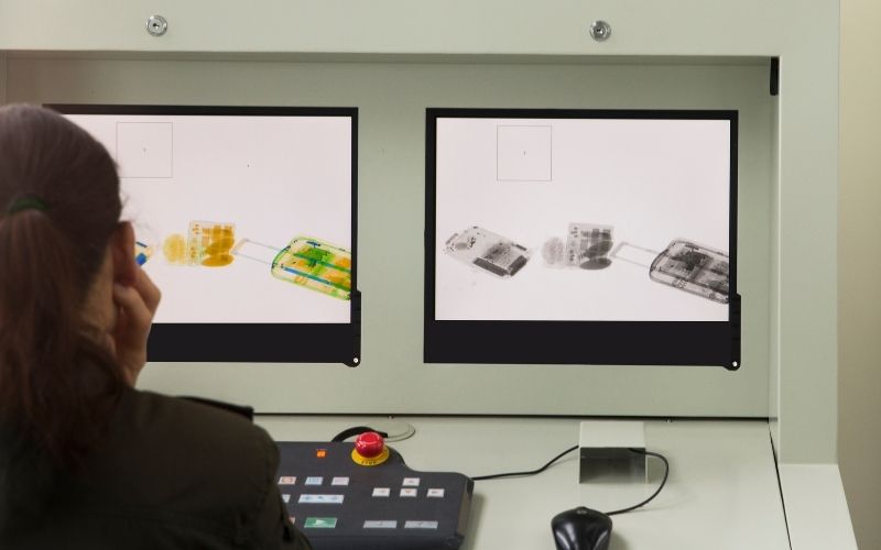 Photo of a person looking at the two monitors showing scanned laggages