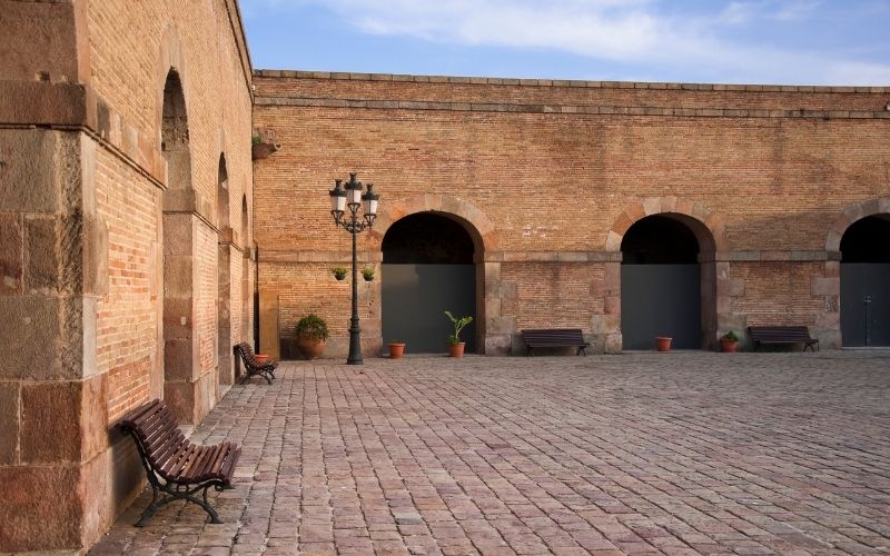 Photo showing walls and pavement made of bricks with some benches at the side of the wall