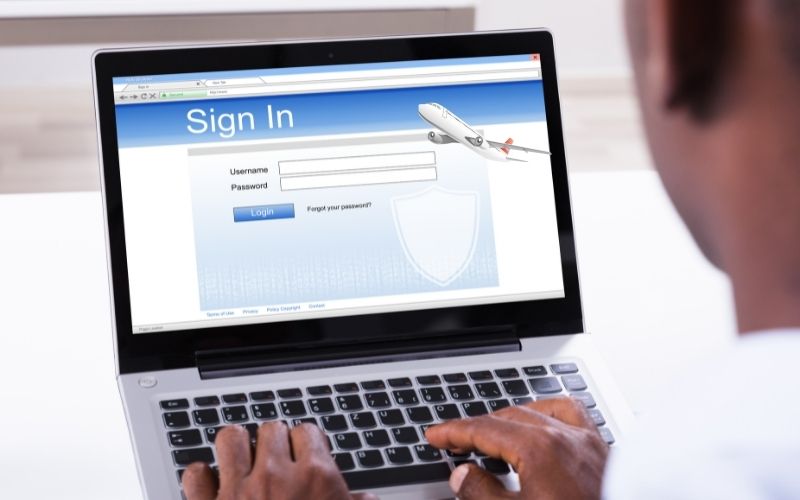 photo of a pair of hands on a laptop showing a website with photo of a plane