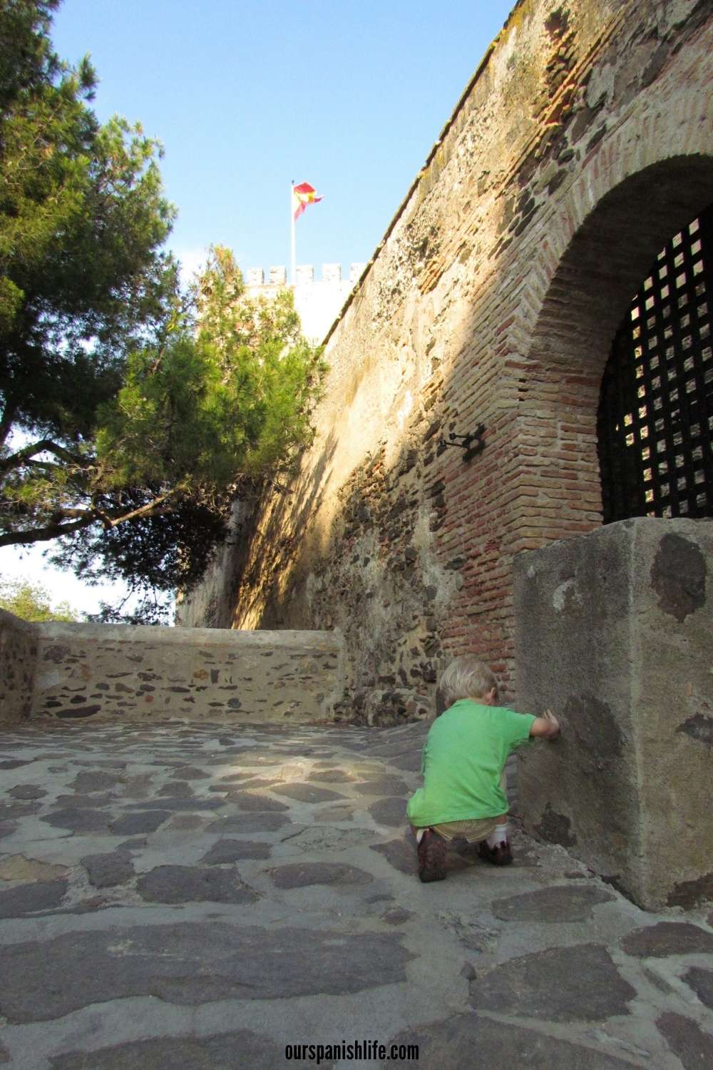 boy in green t-shirt playing in front of castle