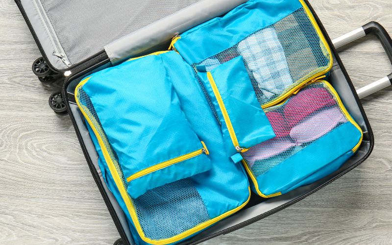 Photo showing an open luggage with set of blue packing cubes