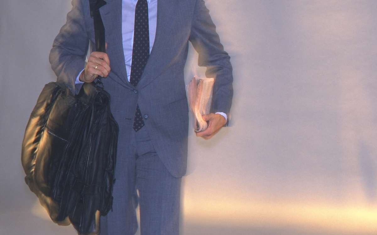 Pgoto showing a man in suit carrying a large bag