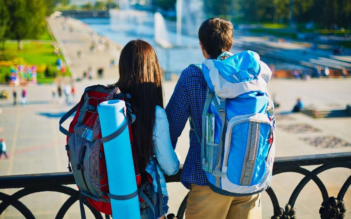 Photo showing a couple carrying large rucksacks o their back looking down at the park